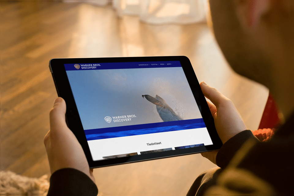Mies katsoo tablettia, jonka näytöllä näkyy Discovery Networksin etusivu.